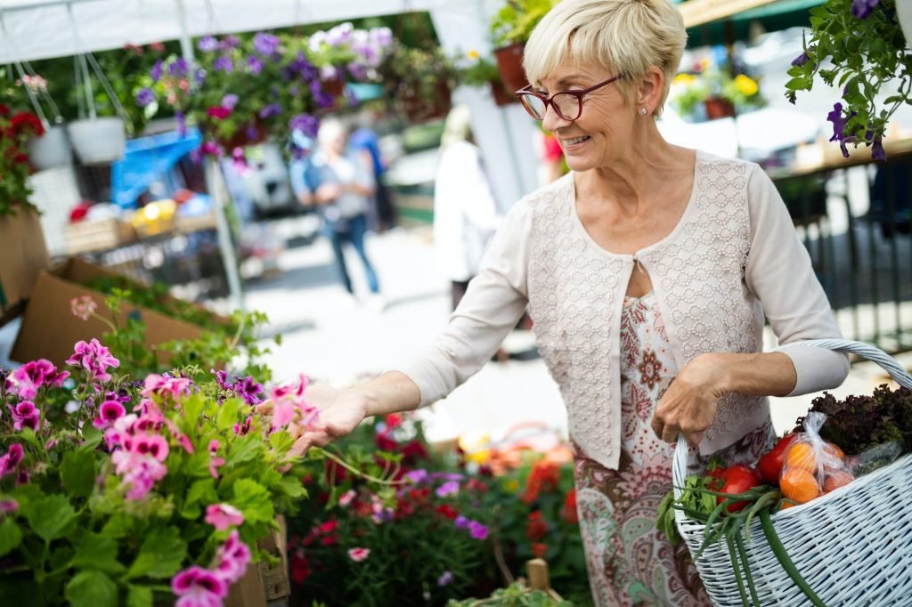 Senior lady shopping for flowers at garden center smiling